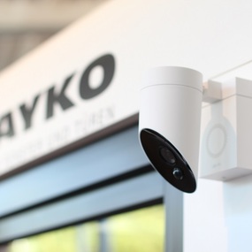 Moderne Überwachungskamera zur Haussicherheit an einer Hauswand neben einem Fenster.